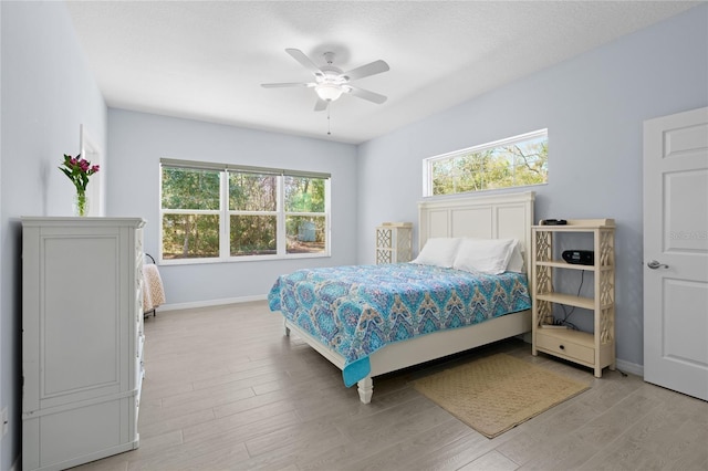 bedroom featuring ceiling fan, light wood finished floors, and baseboards