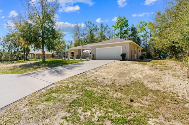 ranch-style house with a garage, stucco siding, driveway, and central air condition unit