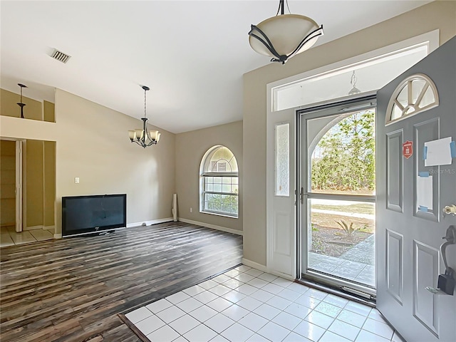 foyer with a chandelier, vaulted ceiling, baseboards, and wood finished floors