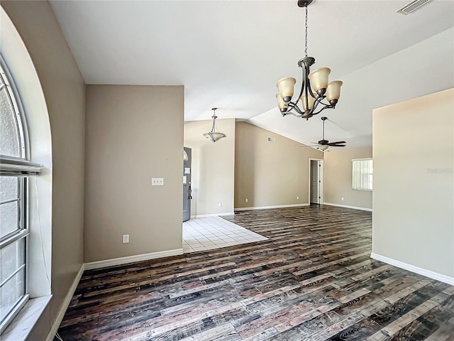 empty room with ceiling fan with notable chandelier, wood finished floors, visible vents, baseboards, and vaulted ceiling