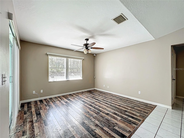 empty room featuring baseboards, a textured ceiling, visible vents, and wood finished floors