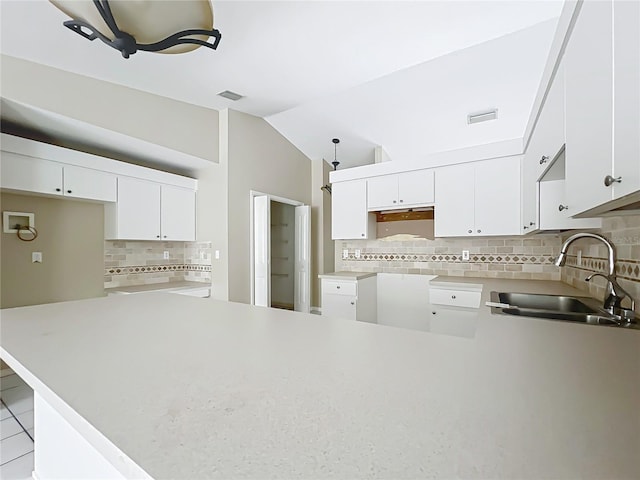 kitchen featuring a peninsula, visible vents, a sink, and lofted ceiling