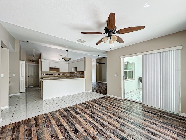 interior space with lofted ceiling, visible vents, white cabinets, open floor plan, and tasteful backsplash