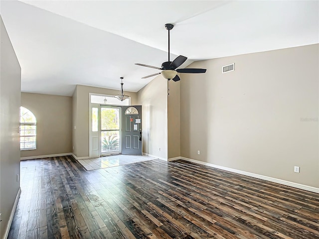 empty room with lofted ceiling, plenty of natural light, wood finished floors, and visible vents