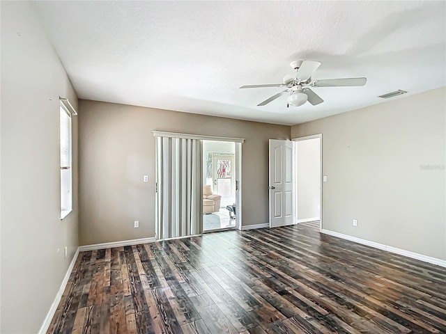 spare room with dark wood-style floors, visible vents, plenty of natural light, and baseboards