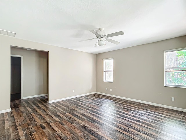 spare room with visible vents, dark wood-style flooring, a ceiling fan, and baseboards