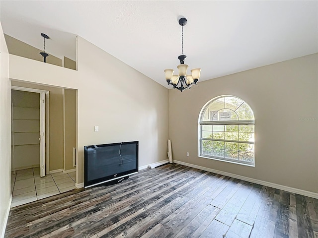 unfurnished living room with lofted ceiling, dark wood-type flooring, a chandelier, and baseboards