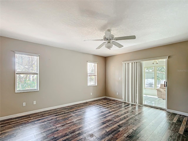 empty room with a textured ceiling, dark wood finished floors, and a wealth of natural light