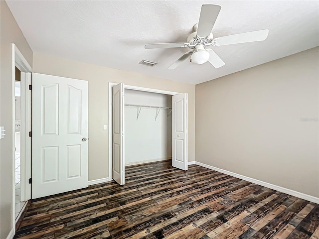 unfurnished bedroom with dark wood-type flooring, a closet, visible vents, and baseboards