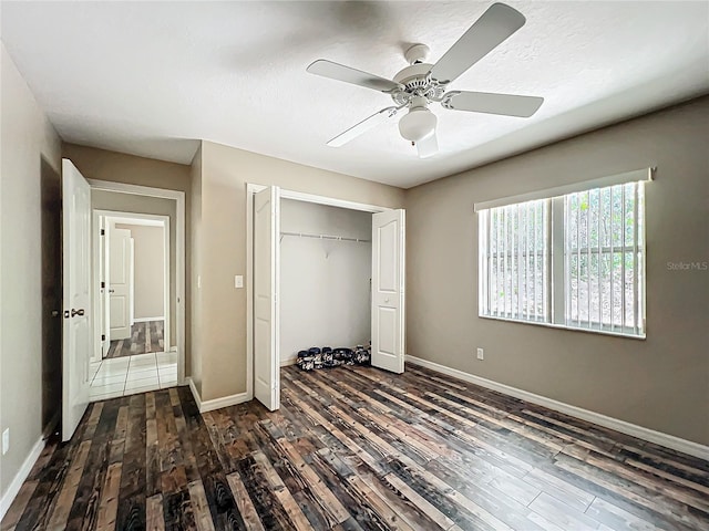 unfurnished bedroom with a closet, dark wood-style flooring, baseboards, and a ceiling fan