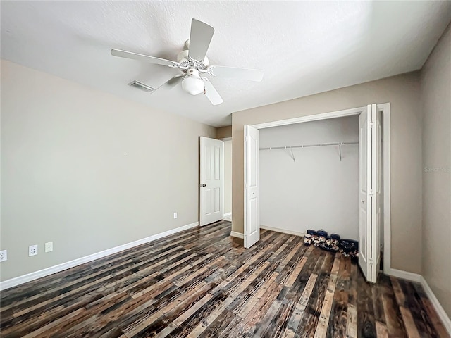 unfurnished bedroom featuring dark wood-style floors, a closet, visible vents, and baseboards