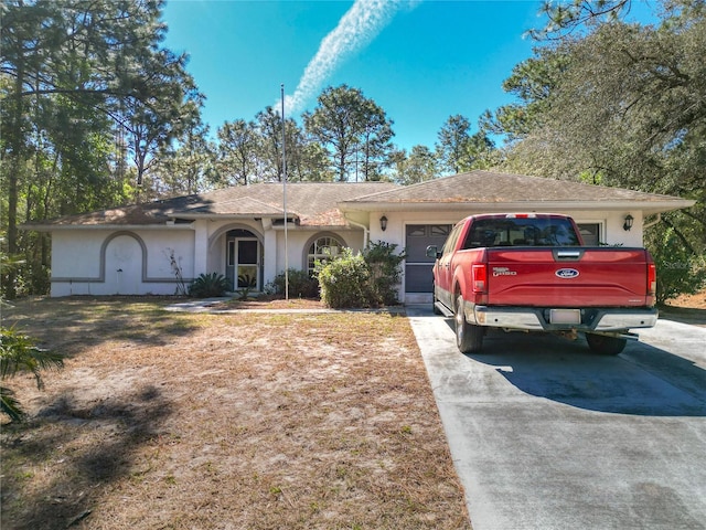 single story home featuring a garage, concrete driveway, and stucco siding