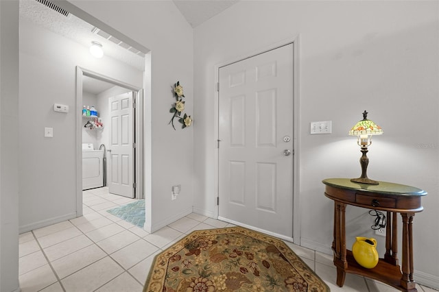 entrance foyer featuring light tile patterned floors, visible vents, washer / dryer, and baseboards