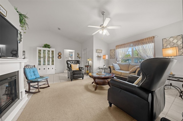 living area with lofted ceiling, light tile patterned flooring, a glass covered fireplace, and a ceiling fan