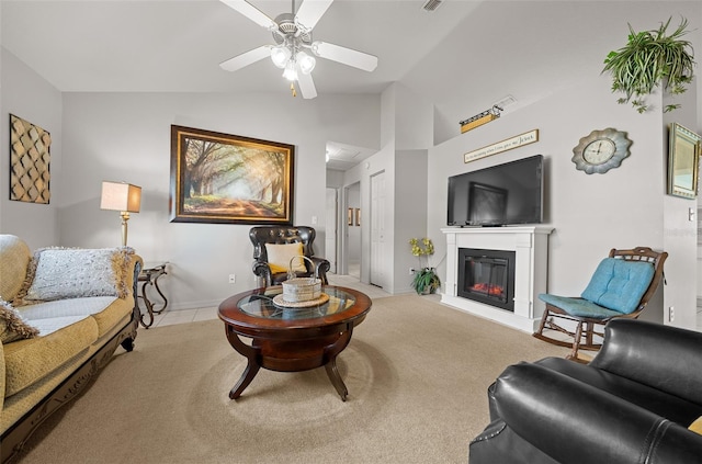 carpeted living room featuring visible vents, a ceiling fan, vaulted ceiling, baseboards, and a glass covered fireplace