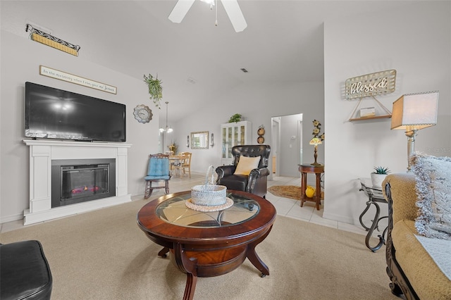 living area featuring lofted ceiling, carpet floors, a glass covered fireplace, and a ceiling fan