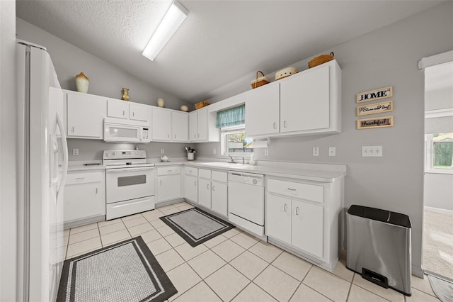 kitchen with lofted ceiling, light countertops, white appliances, and light tile patterned flooring