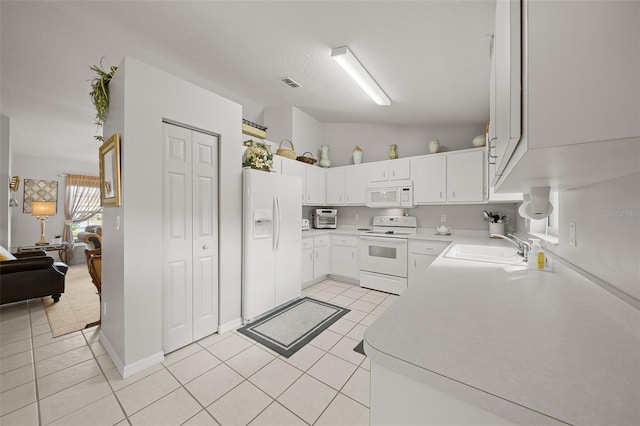 kitchen featuring light tile patterned floors, light countertops, visible vents, a sink, and white appliances