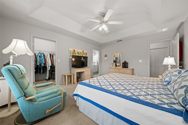 carpeted bedroom with visible vents, a tray ceiling, a walk in closet, and a closet