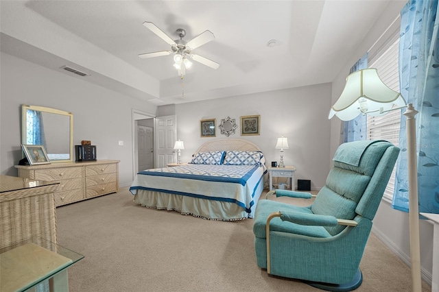 carpeted bedroom with ceiling fan, visible vents, a raised ceiling, and baseboards