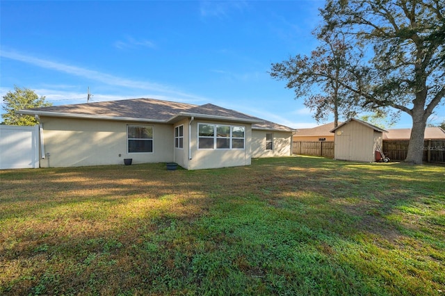 back of property with a fenced backyard, a lawn, an outdoor structure, and stucco siding