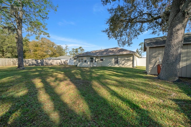 view of yard featuring a fenced backyard, a shed, and an outbuilding