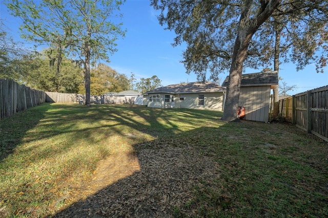 view of yard featuring a fenced backyard, a storage unit, and an outbuilding