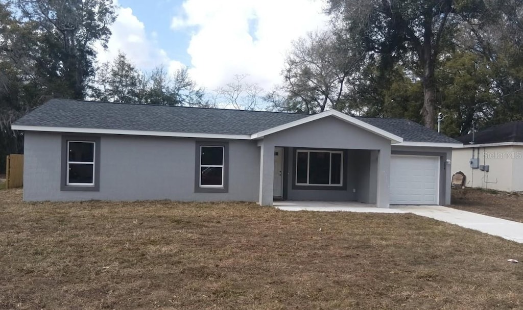 single story home featuring a garage, driveway, a front yard, and stucco siding