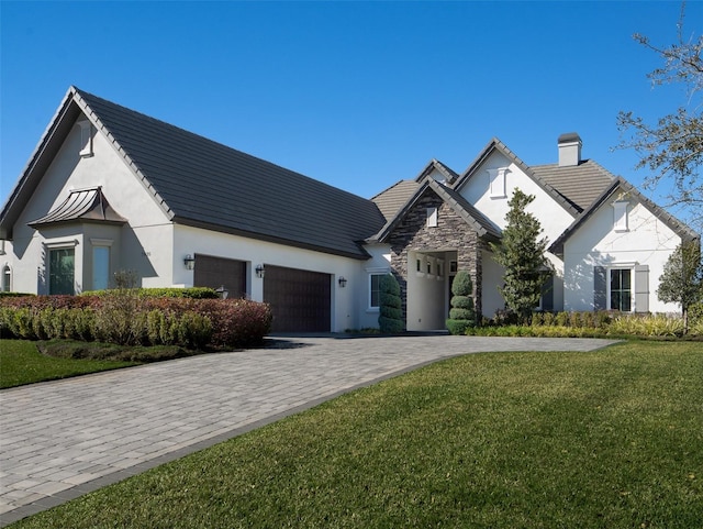 view of front of property with a front yard, stucco siding, a garage, stone siding, and decorative driveway