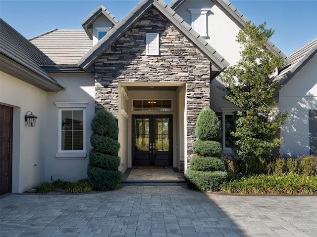 doorway to property featuring french doors, stone siding, and stucco siding