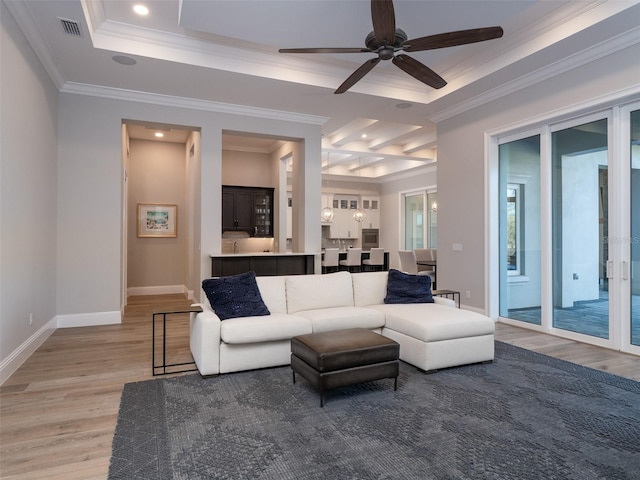 living room featuring visible vents, a raised ceiling, light wood-style floors, and crown molding