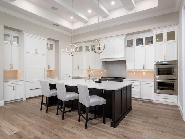 kitchen featuring light wood-type flooring, a breakfast bar area, a kitchen island with sink, and light countertops