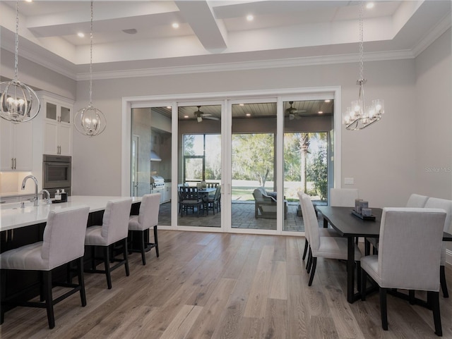 dining space with ceiling fan with notable chandelier, recessed lighting, a raised ceiling, and light wood-type flooring