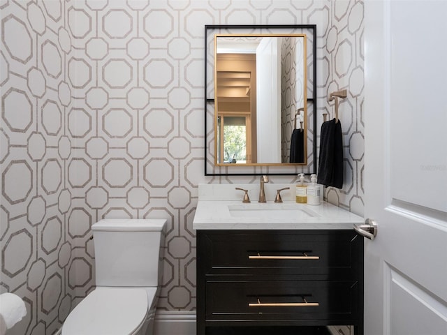 half bathroom with wallpapered walls, toilet, and vanity