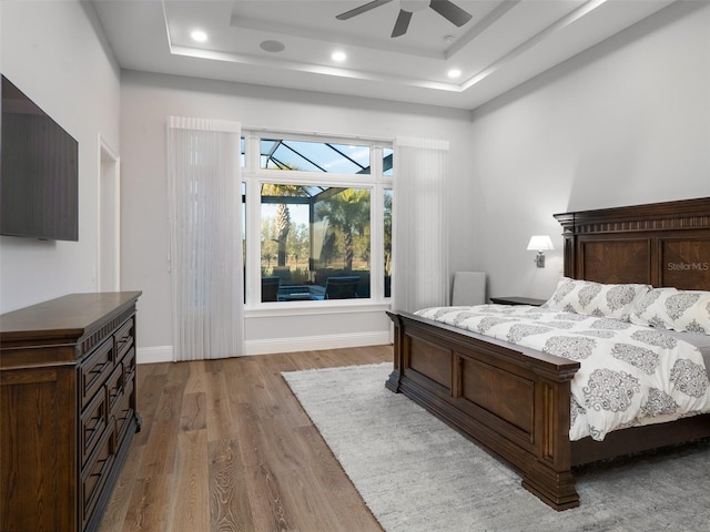 bedroom featuring baseboards, a tray ceiling, and wood finished floors