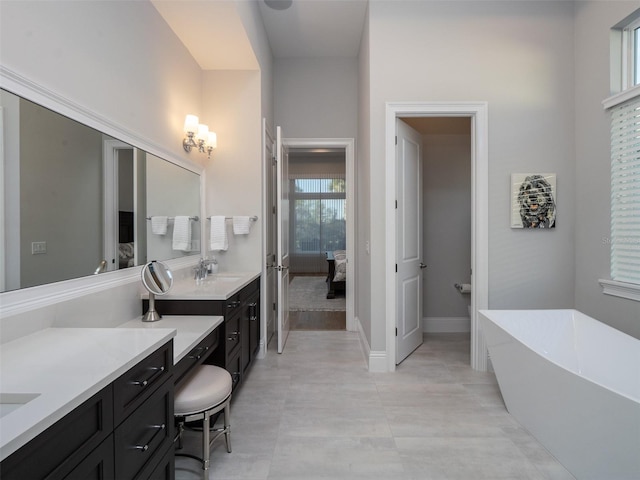 ensuite bathroom with vanity, a freestanding tub, baseboards, and connected bathroom