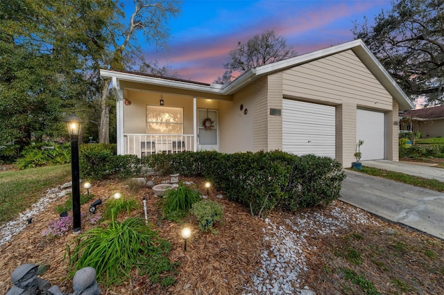 ranch-style home featuring a garage, covered porch, and concrete driveway