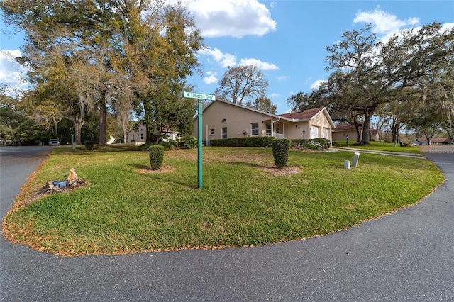 view of front of home with a garage, aphalt driveway, a front lawn, and stucco siding