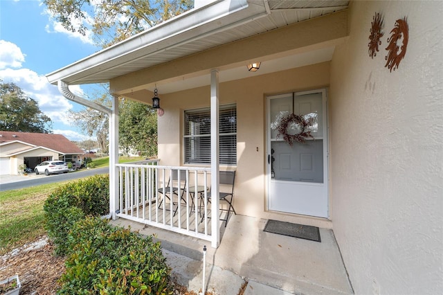 doorway to property with a porch and stucco siding