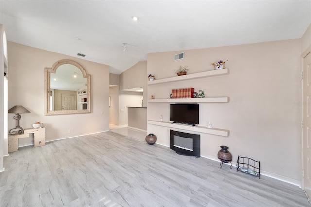 unfurnished living room featuring baseboards, visible vents, vaulted ceiling, and wood finished floors