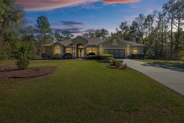 ranch-style house featuring a yard, an attached garage, driveway, and stucco siding