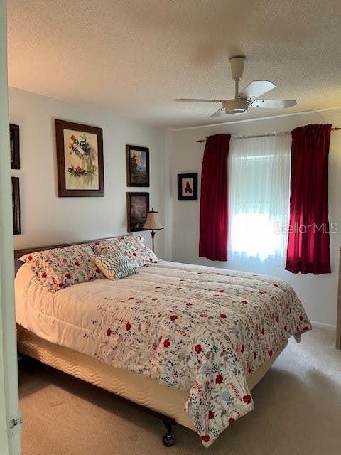 bedroom featuring carpet floors, a textured ceiling, and a ceiling fan