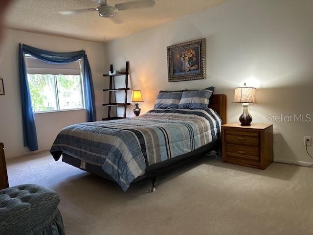 bedroom with light carpet, ceiling fan, and a textured ceiling