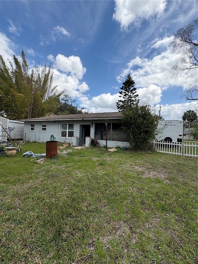 rear view of house featuring a yard, a sunroom, and fence