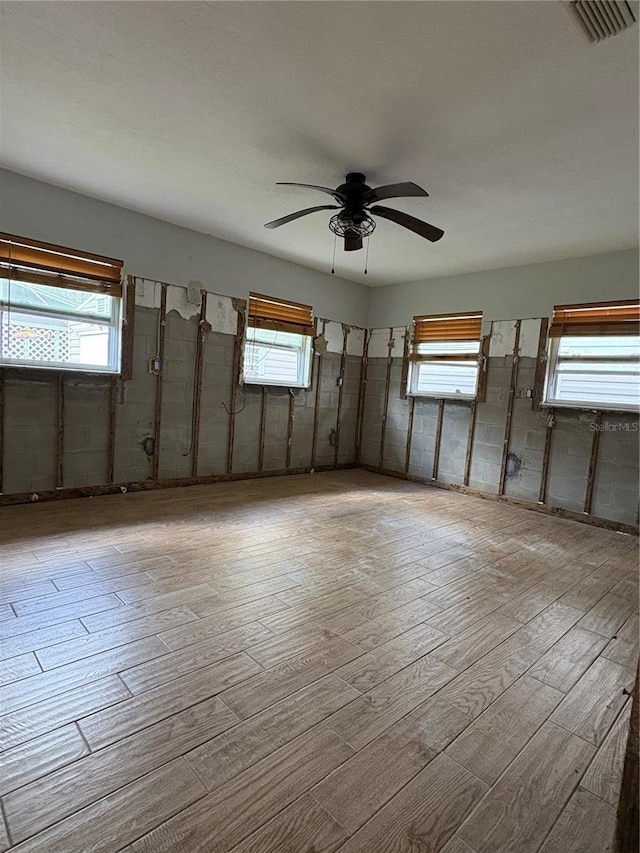 unfurnished room with a ceiling fan, wood finished floors, and visible vents