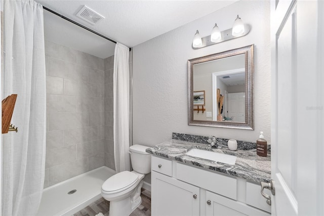 full bathroom with a textured wall, toilet, vanity, visible vents, and a shower stall