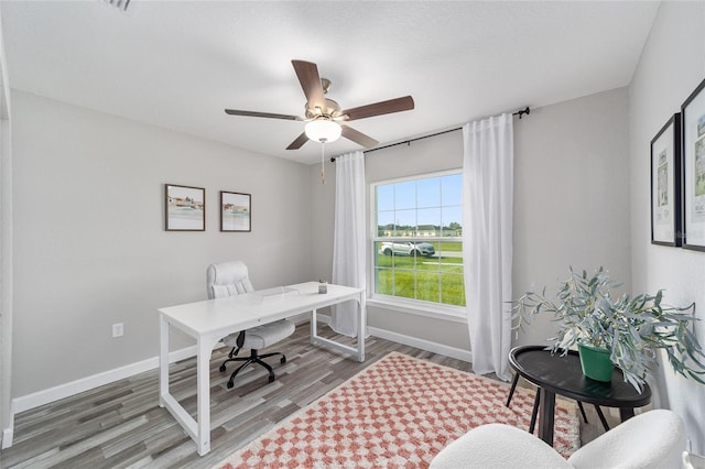 office area featuring a ceiling fan, light wood-type flooring, and baseboards