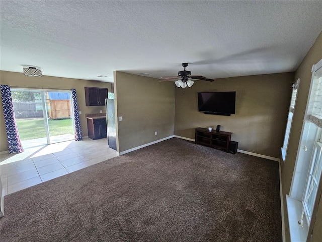 unfurnished living room featuring tile patterned flooring, carpet, a ceiling fan, and a textured ceiling