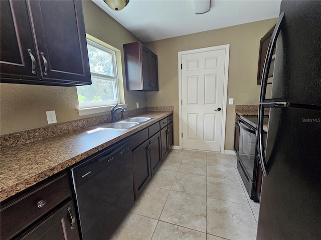 kitchen with light tile patterned floors, baseboards, dark countertops, black appliances, and a sink