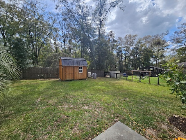 view of yard featuring a fenced backyard, a storage unit, and an outbuilding